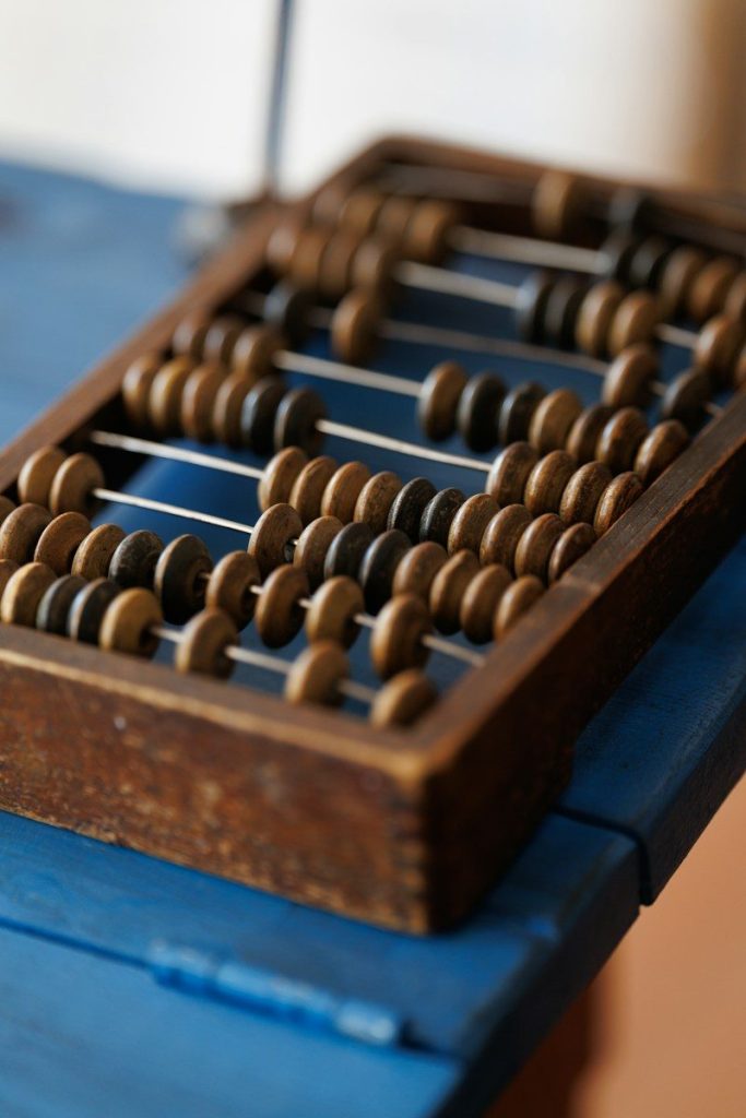An old wooden abacus rests on a blue surface